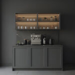 Noirline Kahve Köşesi, modern tasarımı, cam vitrin detayları ve entegre LED aydınlatmasıyla yaşam alanlarınıza şıklık ve fonksiyonellik kazandırır. Siyah çerçeveli cam vitrin bölümleri, fincan ve bardak koleksiyonunuzu estetik bir şekilde sergilerken, geniş tezgâh alanı kahve makineleri ve aksesuarlar için ideal kullanım sunar. Minimal çizgilere sahip gövde yapısı, modern ve çağdaş dekorasyon stilleriyle mükemmel uyum sağlar. LED aydınlatmalı raflar, hem görsel bir ambiyans oluşturur hem de ürünlerinizi ön plana çıkarır. Alt bölümde yer alan geniş depolama alanları sayesinde kahve ekipmanları, kapsüller ve servis ürünleri düzenli bir şekilde saklanabilir. Noirline Kahve Köşesi, mutfak, salon ve ofis ortamlarında özel bir kahve alanı oluşturmak isteyenler için tasarlanmıştır. Şık görünümü, dayanıklı malzemesi ve fonksiyonel yapısıyla hem dekoratif hem de kullanışlı bir çözümdür.